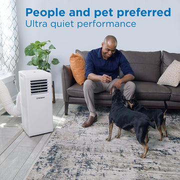 Westinghouse | WPac8000 Portable Air Conditioner shown in use in a living room with a man sitting on a couch petting his dogs with words at the top of the image reading - people and pet preferred ultra quiet performance